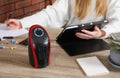 Compact electric heater on wooden table near woman indoors, closeup