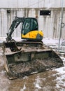 Compact excavator working at construction site during snowfall Royalty Free Stock Photo