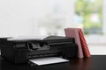 Compact home printer on desk with books against blurred background Royalty Free Stock Photo
