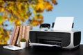 Compact home printer on desk with books against blurred background Royalty Free Stock Photo