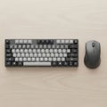 A compact mechanical keyboard and wireless mouse rest on a light wood surface Royalty Free Stock Photo