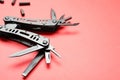 Compact portable black multitool and details on red background, closeup. Space for text Royalty Free Stock Photo