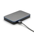 Compact portable external hard drive connected to a charging cable on a plain background Royalty Free Stock Photo