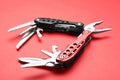 Compact portable multitool on red background, closeup
