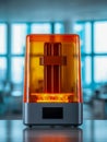 Compact resin 3d printer with translucent orange cover sitting on a reflective surface in a bright modern workspace equipped for Royalty Free Stock Photo