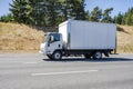 Compact small cab over rig semi truck with box trailer running on the highway for local delivery Royalty Free Stock Photo