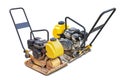 A compact vibrating plate machine is placed. The machine is designed for soil compaction, compacting the ground beneath it. Men at Royalty Free Stock Photo
