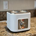 Compact white egg cooker on a granite countertop, featuring three slots on top with a Royalty Free Stock Photo