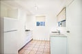 Compact white fitted kitchen with tiled floor