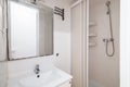 Compact white old tiled bathroom with shower and sink in need of renovation. Concept of preparing the premises for the