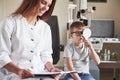 Compairing results. Doing testing in the oculist office with child. Doctor notes data Royalty Free Stock Photo