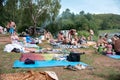 Companies of people rest closely on the bedspreads on the wooded shore of the lake on a summer day Royalty Free Stock Photo