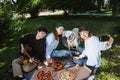 Company of beautiful young people and dog having an outdoor lunch. Royalty Free Stock Photo