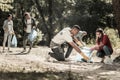 Company of diligent volunteers working cleaning up the trash left in forest Royalty Free Stock Photo