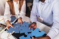 employees playing game and joining pieces of puzzle during team building activity Royalty Free Stock Photo