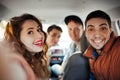 A company of four friends makes selfie inside the car