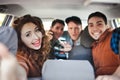 A company of four friends makes selfie inside the car