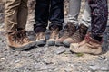 Company four tourists only legs together in brown trekking hiking boots with laces on rocky cliff. Concept freedom, travel