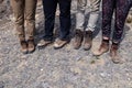 Company four tourists together feet in brown trekking hiking boots with laces on rocky cliff. Concept freedom, travel lifestyle