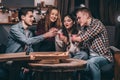 company of four young guys, girls clink cardboard cups at home pizza party