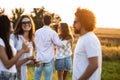 Company of friends chatting in the open air on a sunny day. In the background a young man embraces a girl. Royalty Free Stock Photo