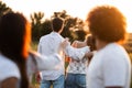 Company of friends in the open air on a sunny day. In the background a young man embraces a girl. Royalty Free Stock Photo