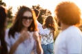 Company of friends in the open air on a sunny day. In the background a young man embraces a girl. Royalty Free Stock Photo