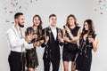 Company of girls and guys dressed in stylish elegant clothes stand together and hold glasses of champagne in hands on Royalty Free Stock Photo