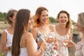 The company of gorgeous female friends having fun, drink wine, and enjoy hills landscape picnic