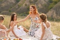 The company of gorgeous female friends having fun, drink wine, and enjoy hills landscape picnic