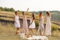 The company of gorgeous female friends having fun and enjoys a summer green hlls picnic, dancing and drink alcohol. People concept