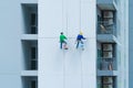 A company group of people, workers or painters, painting a wall on a high rise office building with cable wires outside in Bangkok Royalty Free Stock Photo