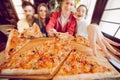 The company of guys in the pizzeria. Four friends in a cafe on the background of a large pizza on a wooden board.