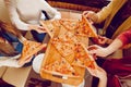 The company of guys in the pizzeria. Hands with pizza top view. Sort hot pizza from the board.