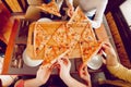 The company of guys in the pizzeria. Hands with pizza top view. Sort hot pizza from the board.