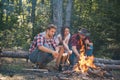 Company having hike picnic nature background. Friends roasting hotdogs on sticks at bonfire and having fun at camp fire Royalty Free Stock Photo