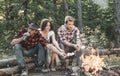 Company having hike picnic nature background. Weekend. Happy young people camping in woods. Hikers sharing impression of Royalty Free Stock Photo