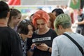 Company of modern informal youth at the festival, couple of girls use phone, youth mob in big city