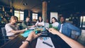 Company owner is talking to his employees at meeting sitting at table while group of young people is looking at him and Royalty Free Stock Photo