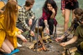 A company of young people cooking mushrooms on fire