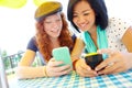 Comparing apps. Two teenage girls sitting outside texting on their cellphones. Royalty Free Stock Photo