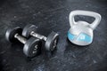 Comparing a pair of dumbbells with a plastic kettlebell. Both lying on the rubber matting of a gym or fitness center. Royalty Free Stock Photo