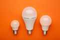 Comparison of different light bulbs on orange background Royalty Free Stock Photo