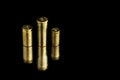 Comparison of sizes of different used bullet shells on a black background with reflection from a tin table top. View of