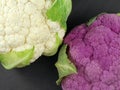 comparson of white and purple cauliflower, top view of different colored vegetables on black background