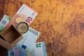 Compass beside a box and Euro banknotes  on an old map Royalty Free Stock Photo