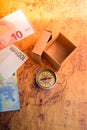 Compass beside a box and Euro banknotes  on an old map Royalty Free Stock Photo