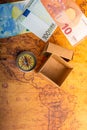 Compass beside a box and Euro banknotes  on an old map Royalty Free Stock Photo