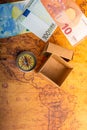 Compass beside a box and Euro banknotes on an old map