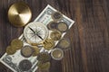 Compass with euro coins, dollar bill on wooden surface Royalty Free Stock Photo
